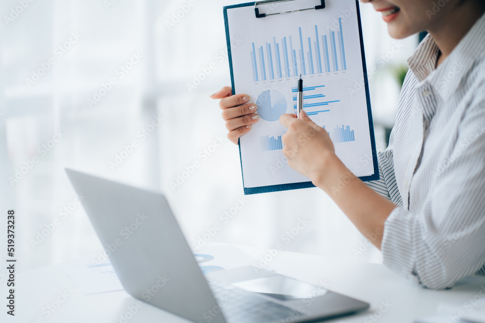 Young businesswoman analyzes cost graphs on desk in conference room with laptop