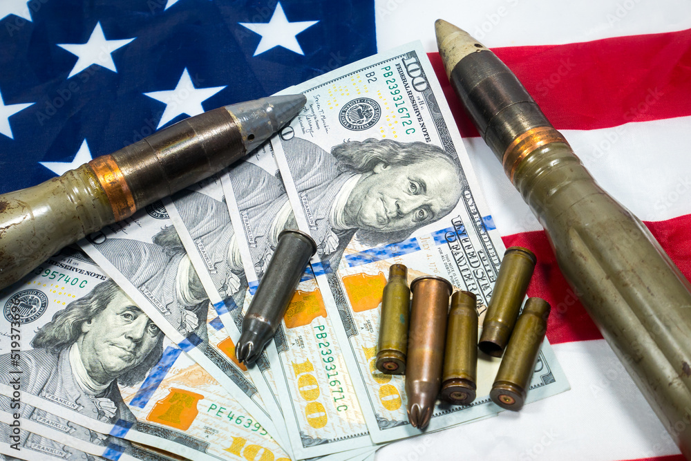American flag with dollars money, bullets, shells, cartridges and projectiles on it. Lend-Lease concept. Army concept. Sales of weapons and ammunition..Military industry, war, global arms trade. American flag with dollars money, bullets, shells, cartridges and projectiles on it. Lend-Lease concept. Army concept. Sales of weapons and ammunition..Military industry, war, global arms trade.