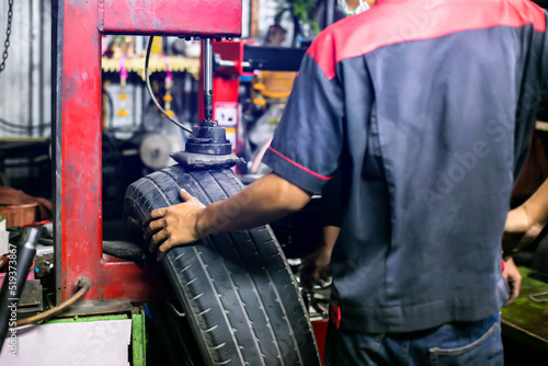 Selective focus to car tire patch machine with blurry mechanic working in car service center. © Koonsiri