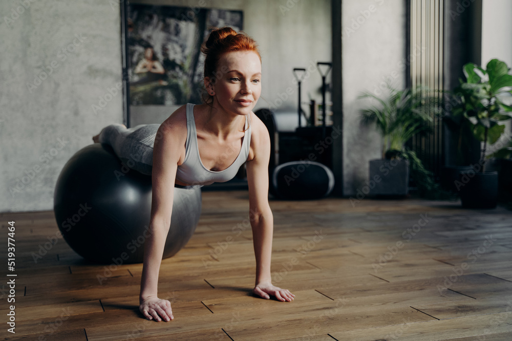 Fit woman balancing on exercise ball in fitness studio during pilates workout Fit woman balancing on exercise ball in fitness studio during pilates workout