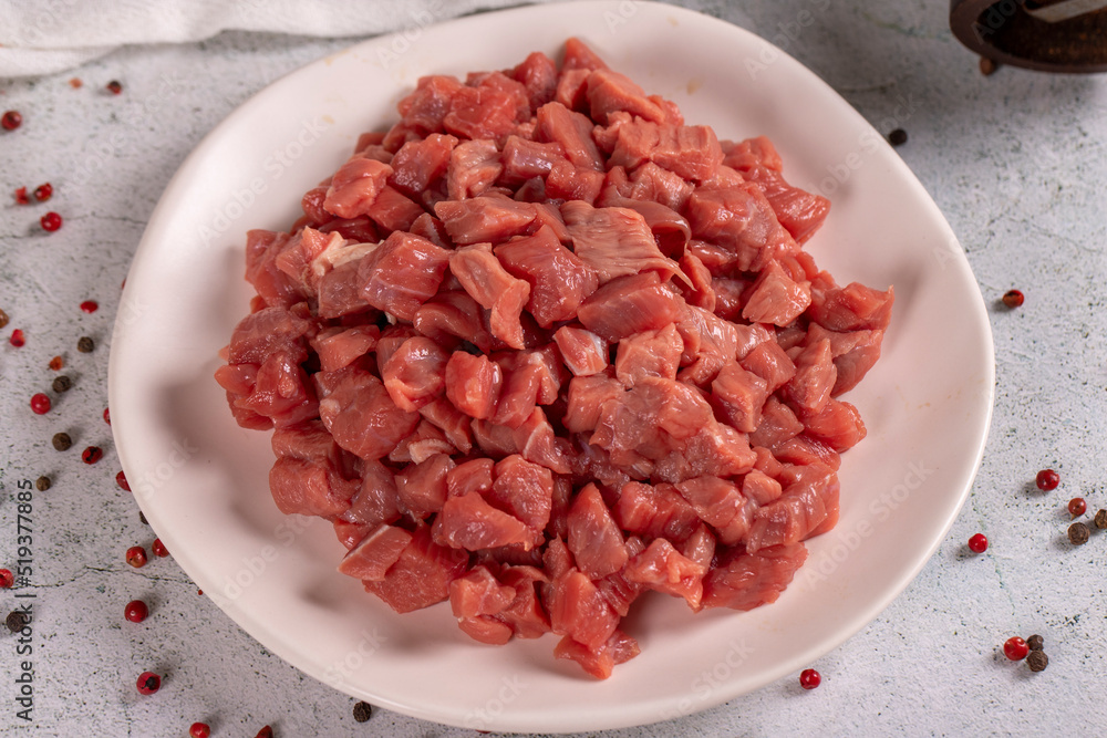 Cubed meat. Red meat in a chopped plate on a stone floor. Butcher products. close up