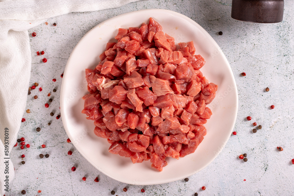 Cubed meat. Red meat in a chopped plate on a stone floor. Butcher products. close up. Top view Cubed meat. Red meat in a chopped plate on a stone floor. Butcher products. close up. Top view