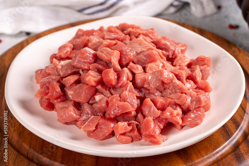 Cubed meat. Red meat in a chopped plate on a stone floor. Butcher products. close up