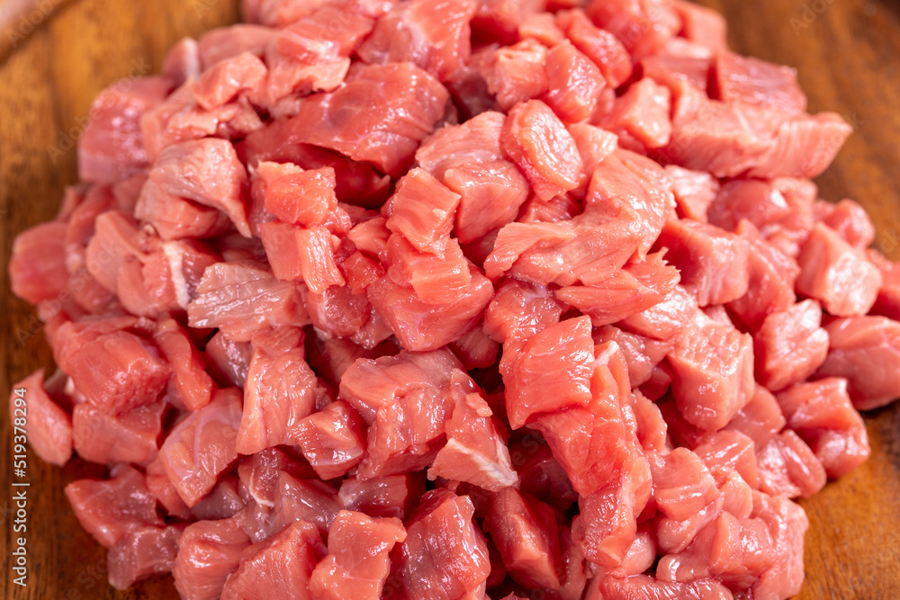 Cubed meat. Chopped red meat in a wooden serving dish on a stone background. Butcher products. close up Cubed meat. Chopped red meat in a wooden serving dish on a stone background. Butcher products. close up