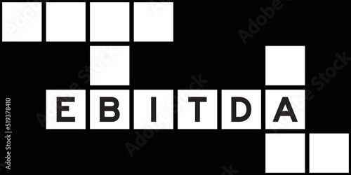 Alphabet letter in word EBITDA (abbreviation of earnings before interest, taxes, depreciation and amortization) on crossword puzzle background