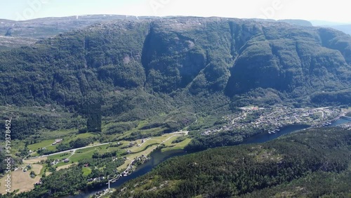 Flying over the mountains and over the green valley with a bird's eye view of the village. Norway mountains and fjord covered with forest. Preservation of nature and ecology. photo