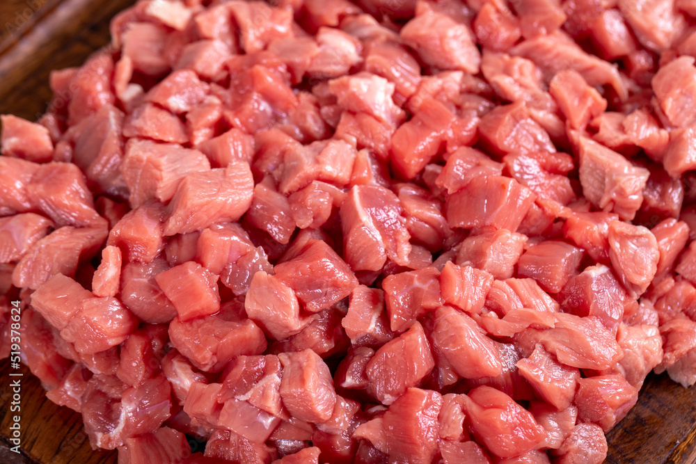 Cubed meat. Chopped red meat in a wooden serving dish on a stone background. Butcher products. close up Cubed meat. Chopped red meat in a wooden serving dish on a stone background. Butcher products. close up
