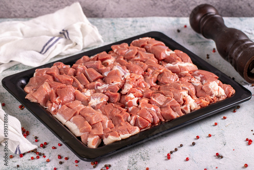 Lamb cubed meat. Chopped red meat in a wooden serving dish on a stone background. Butcher products.