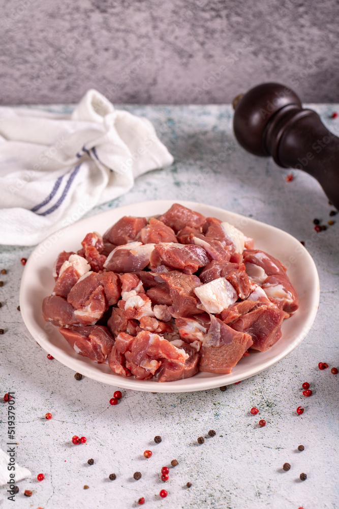 Lamb cubed meat. Chopped red meat in a plate on a stone floor. Butcher products. close up Lamb cubed meat. Chopped red meat in a plate on a stone floor. Butcher products. close up
