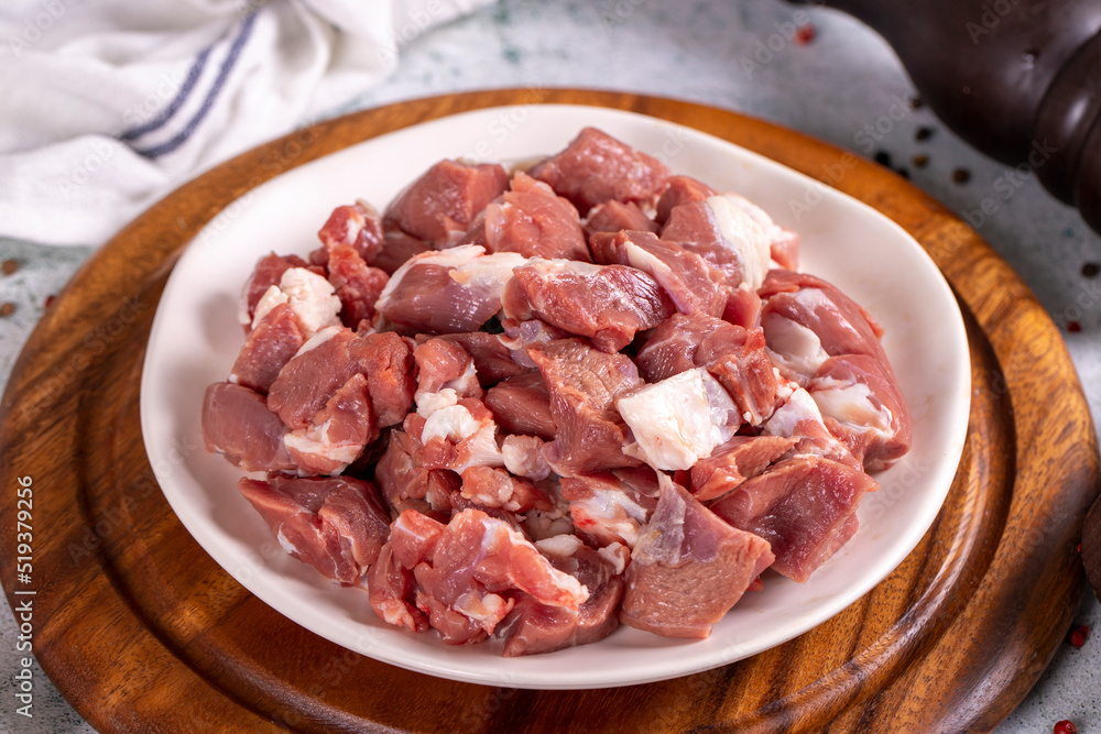Lamb cubed meat. Chopped red meat in a plate on a stone floor. Butcher products. close up Lamb cubed meat. Chopped red meat in a plate on a stone floor. Butcher products. close up
