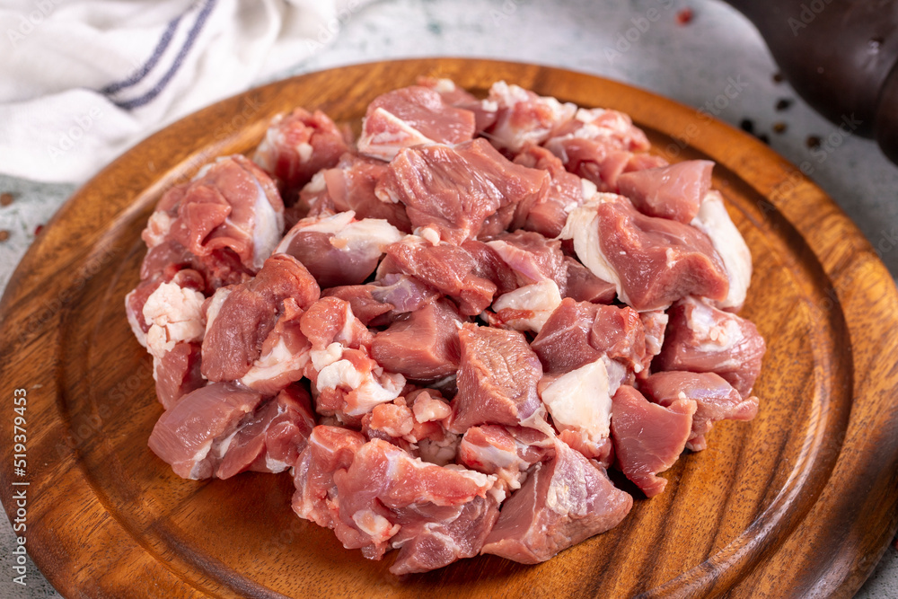Lamb cubed meat. Chopped red meat in a wooden serving dish on a stone background. Butcher products. close up