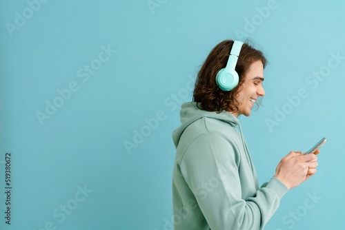 Young smiling man with long hair in headphones holding phone