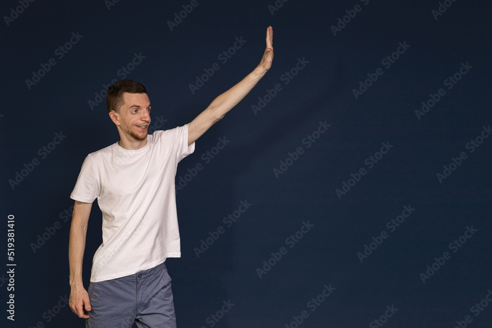 A man in a white T-shirt stands on a blue background and says hello A man in a white T-shirt stands on a blue background and says hello