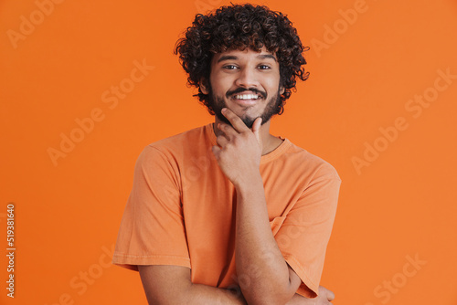 Fototapeta Portrait of young indian handsome curly smiling man touching chin