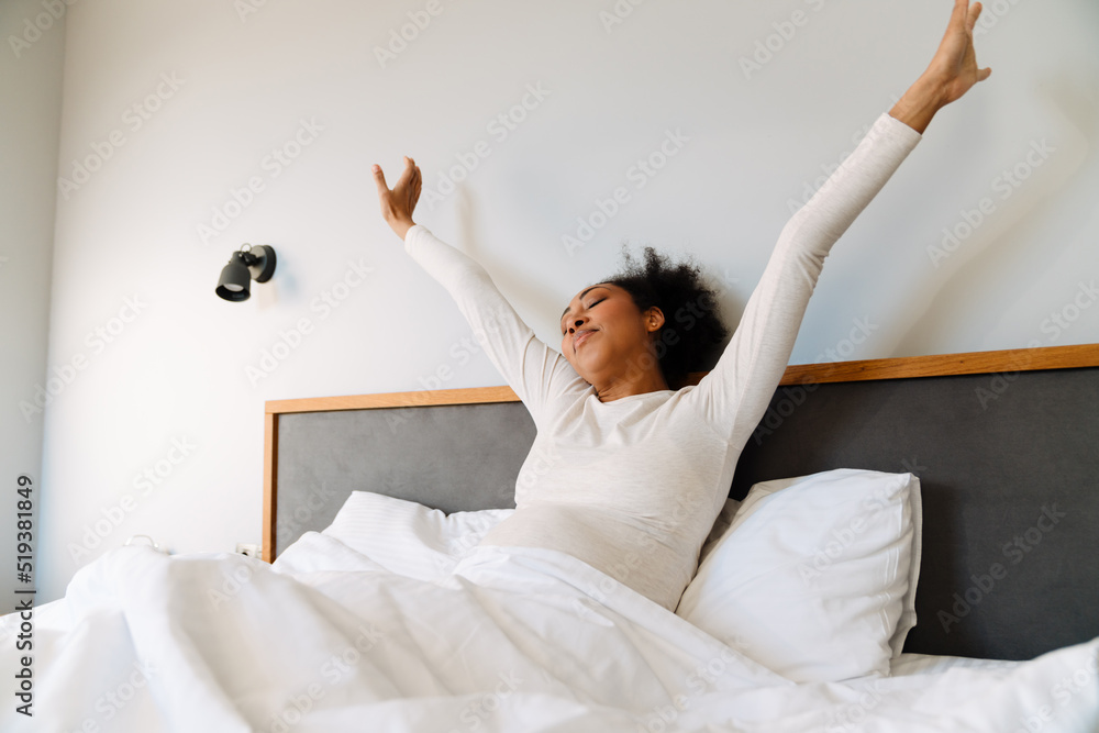 Adult beautiful pregnant african woman stretching while liying on bed Adult beautiful pregnant african woman stretching while liying on bed