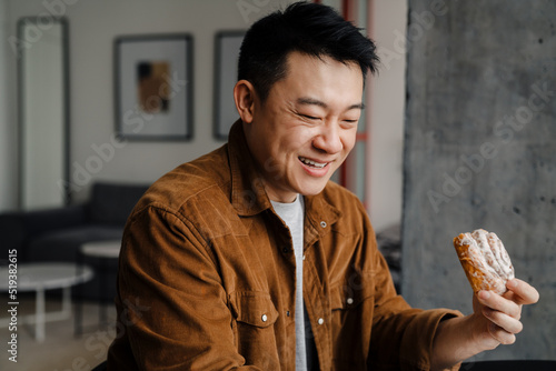 Asian man using tablet computer while having breakfast in kitchen