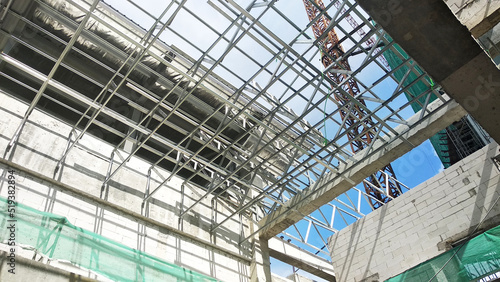 SELANGOR, MALAYSIA -JUNE 16, 2021: Construction workers install trusses and roofing sheets at construction sites. Lightweight roof trusses used are more economical, sturdy and fast.