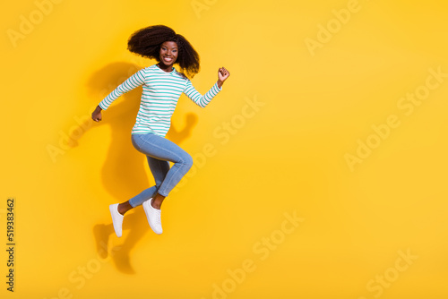 Full body photo of carefree excited girl running jumping empty space ad isolated on yellow color background