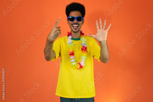 Black man football fan. Man in yellow shirt isolated on orange background.