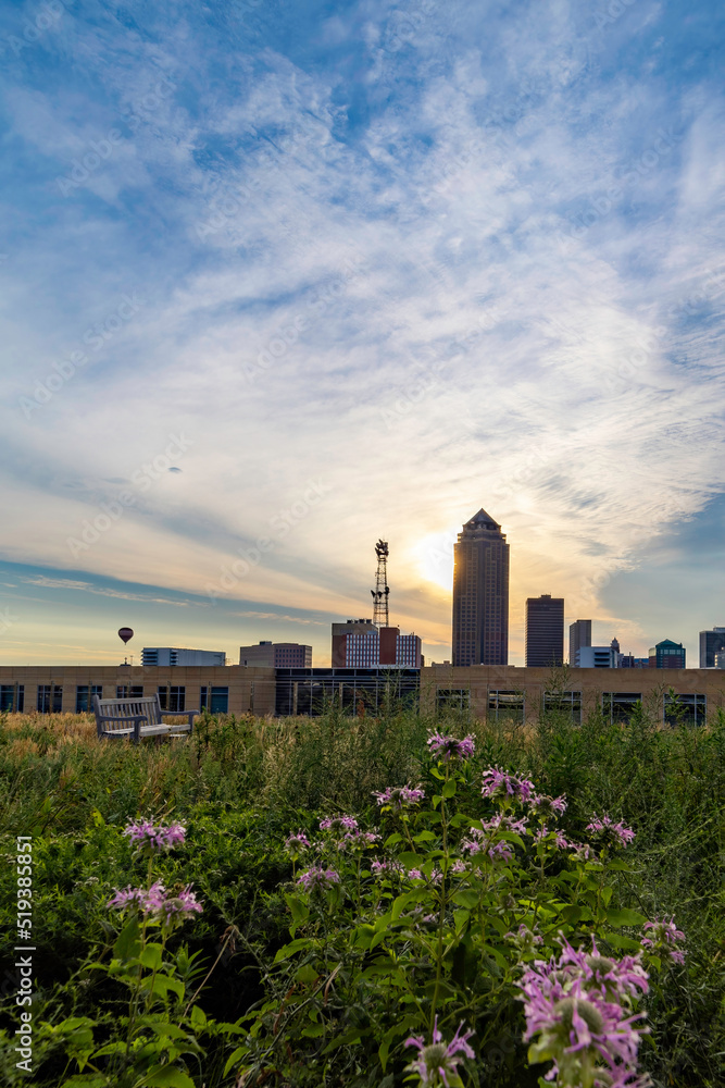 Hot air balloon rises over the Des Moines skyline at sunrise as seen from a roof garden.