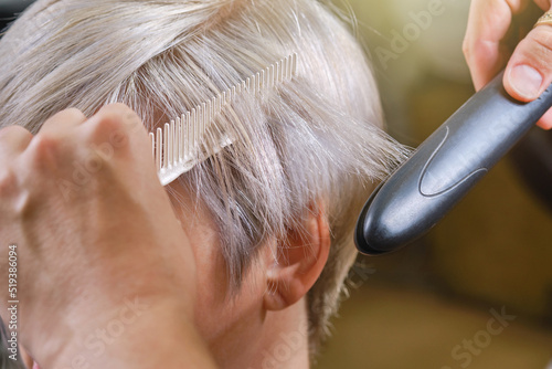 Professional hairdresser drying hair with a hair straightener client. Shallow depth of field