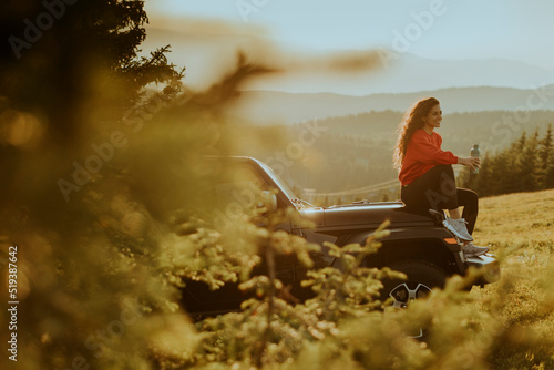 Young woman relaxing on a terrain vehicle hood at countryside