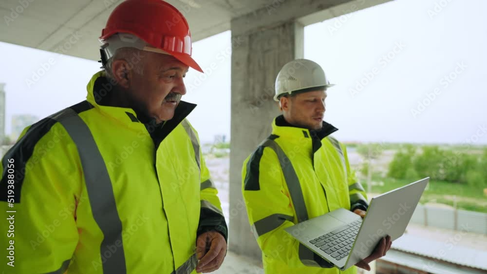 civil engineer with laptop and foreman in hardhats are examining under-construction building civil engineer with laptop and foreman in hardhats are examining under-construction building