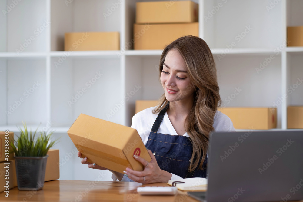 Young beautiful happy asian business woman owner of SME online using laptop receive order from customer with parcel box packaging at her startup home office, online business seller and delivery Young beautiful happy asian business woman owner of SME online using laptop receive order from customer with parcel box packaging at her startup home office, online business seller and delivery