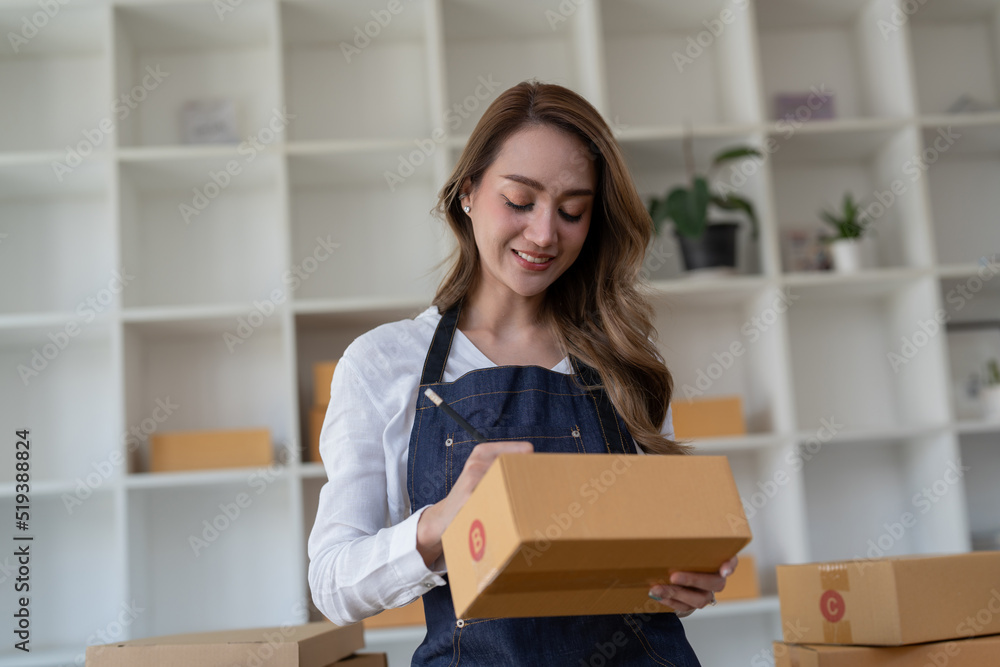 Portrait young attractive asia female owner startup business look at camera work happy with box at home prepare parcel delivery in sme supply chain, procurement, omnichannel commerce online concept. Portrait young attractive asia female owner startup business look at camera work happy with box at home prepare parcel delivery in sme supply chain, procurement, omnichannel commerce online concept.