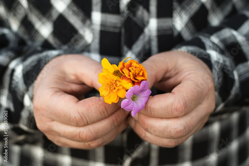 A caucasian man holds a small bouquet of yellow flowers in his hands. Close-up with a blurred background.