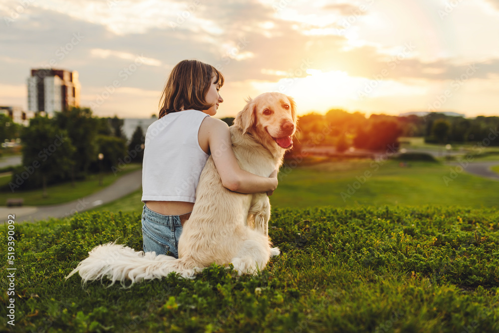 Portrait of teenage girl petting golden retriever outside in sunset view from back Portrait of teenage girl petting golden retriever outside in sunset view from back