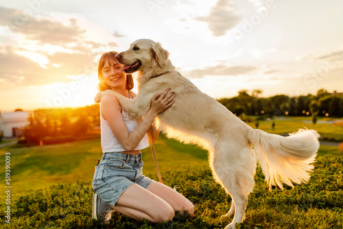 Portrait of teenage girl petting golden retriever outside in sunset