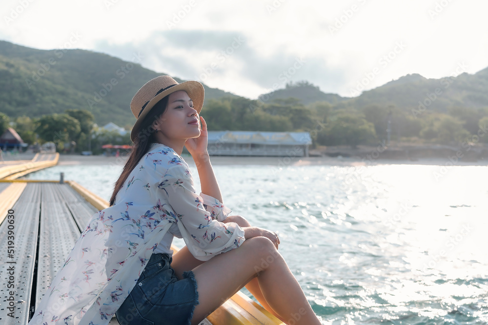 Happy woman wearing straw hat relaxing and watching views of sea and sky on tropical beach travel summer holidays. Beautiful young model tourist enjoy traveling to exotic nature in leisure time.