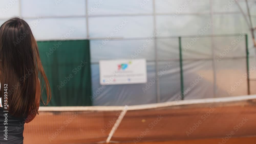 Brunette woman hitting the ball on the tennis court above the net Brunette woman hitting the ball on the tennis court above the net