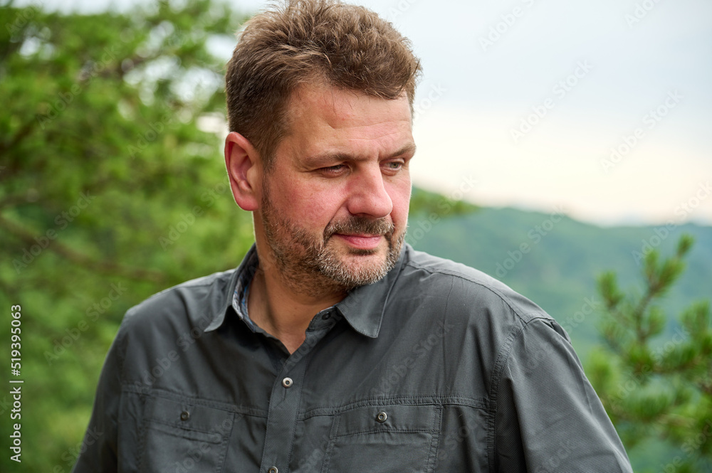 a middle-aged man of 45 year old is looking thoughtfully sideways on a cloudy day with pine tree branches in the background a middle-aged man of 45 year old is looking thoughtfully sideways on a cloudy day with pine tree branches in the background