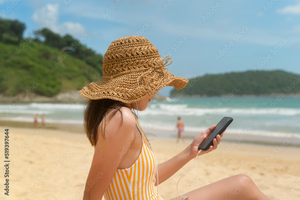 Fototapeta premium Young Beautiful woman in Bikini listening to music and using smartphone on the beach, Summer, vacation, holidays, Lifestyles concept.