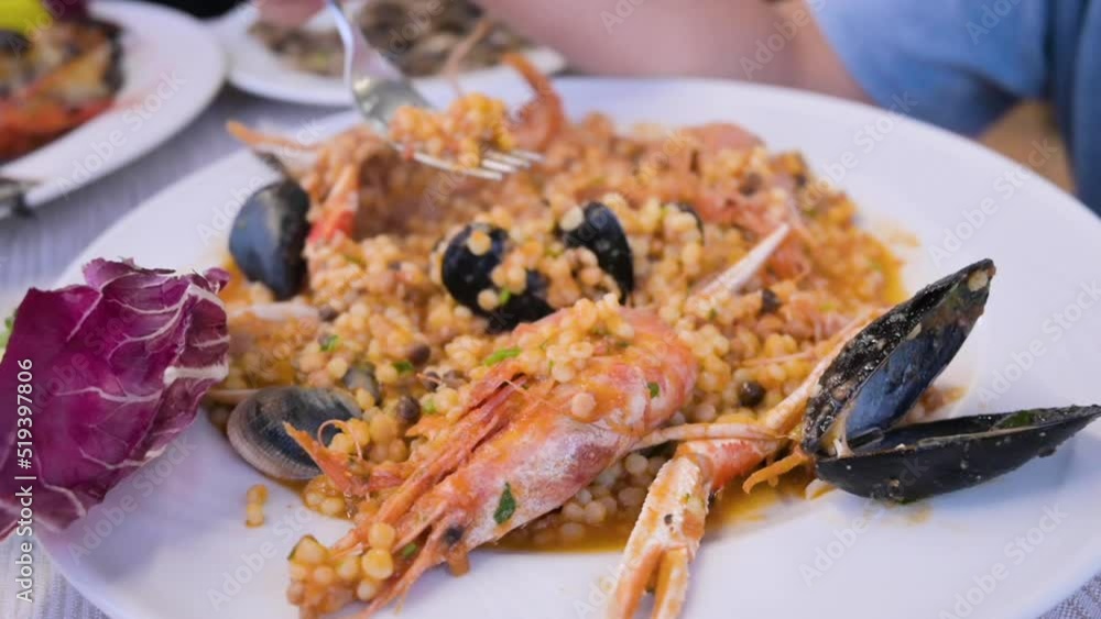 Italian pasta. Fregula with seafood. Traditional small round Sardinian pasta with shellfish, langoustine, mussels and vongole. in a restaurant. High quality FullHD footage Italian pasta. Fregula with seafood. Traditional small round Sardinian pasta with shellfish, langoustine, mussels and vongole. in a restaurant. High quality FullHD footage