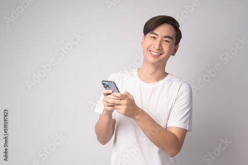 Young asian man using smartphone over white background, technology concept. .. © tonefotografia