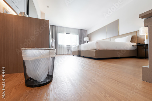 A container trash in the room with plastic inside it in hotel and resort bedroom with wooden floor and furniture background. photo