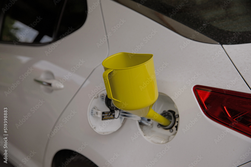 A can for pouring gasoline from the canister into the car. Yellow watering can in the fuel hole. Gasoline collapse. Alternative method of filling the car