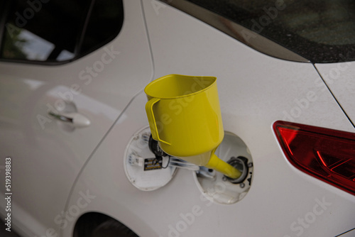 Obraz na płótnie A can for pouring gasoline from the canister into the car. Yellow watering can in the fuel hole. Gasoline collapse. Alternative method of filling the car w salonie