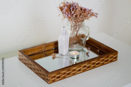 Dried flowers vase, soap, skin care products and candle on mirror tray. Aesthetic minimalist composition.
