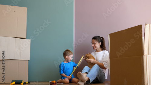 Young mother and a funny child have fun during the renovation. Renovation of the rooms of the house, cardboard boxes, a new house and moving.