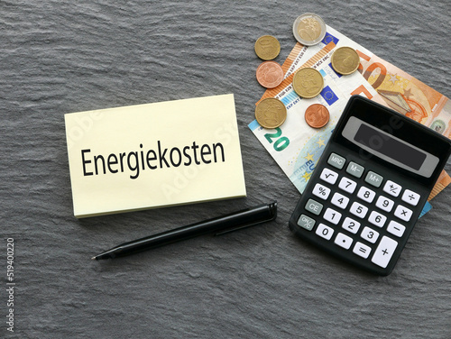 Das Wort Energiekosten auf einem Notizblock  mit Euro Banknoten und Taschenrechner. photo
