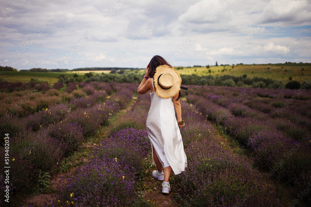 young beautiful elegant asian woman in white dress holding bouquet of lavender flower walking in bloom field outdoors leisure lifestyle