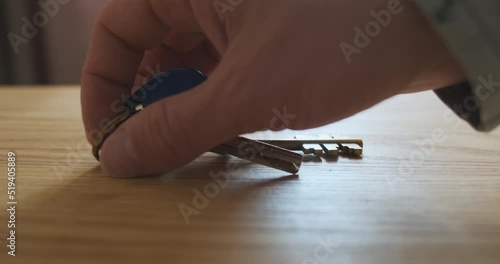 Man's hand takes the keys to the apartment from the table. Close-up, indoors. Concept of leaving the house, take with you, close the apartment, protection from thieves.