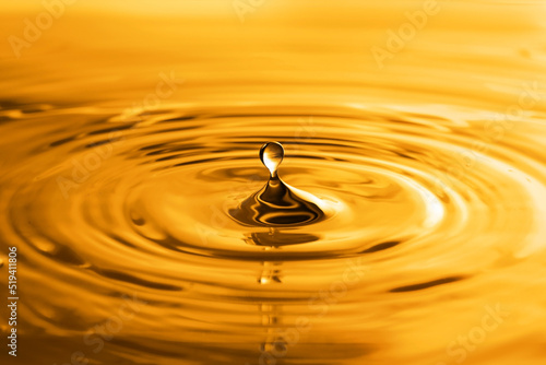 Splash of golden oily liquid with drop as background, closeup