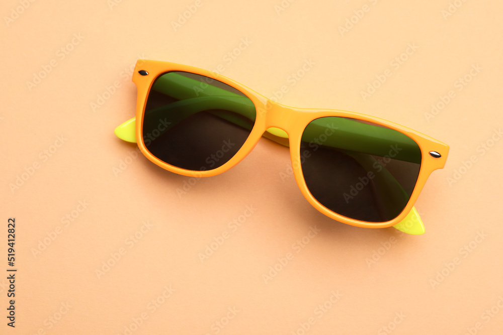 New stylish elegant sunglasses on beige background, top view