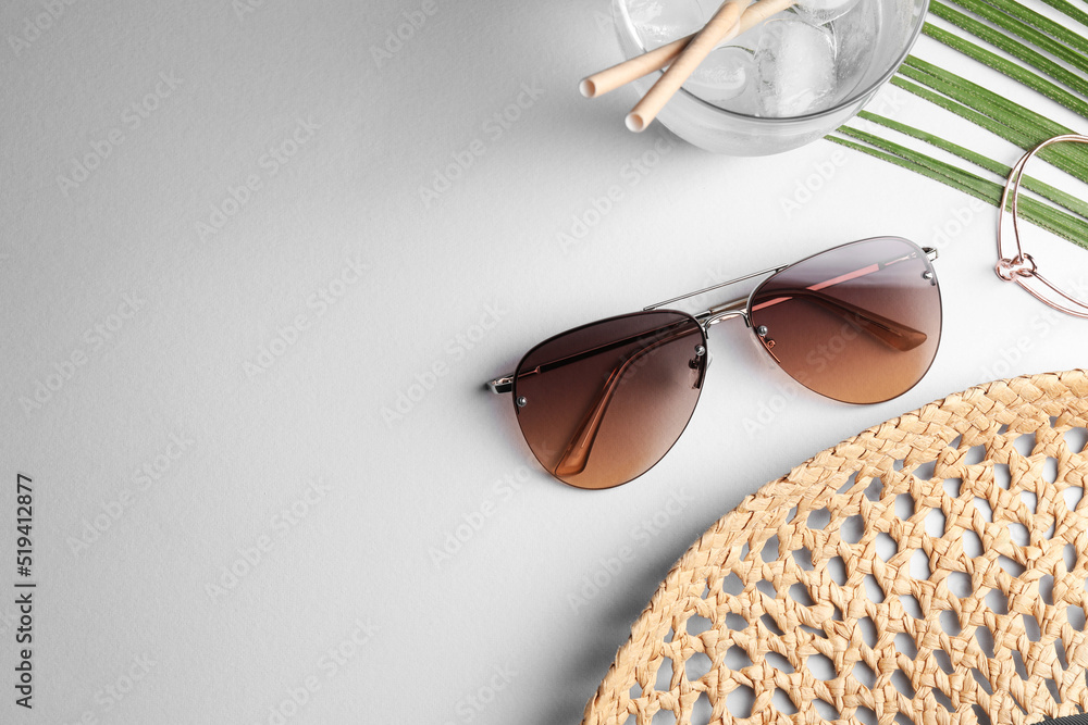 New stylish sunglasses, glass of water, armlet and wicker hat on white table, flat lay. Space for text New stylish sunglasses, glass of water, armlet and wicker hat on white table, flat lay. Space for text