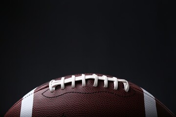 American football ball on black background, closeup. Space for text